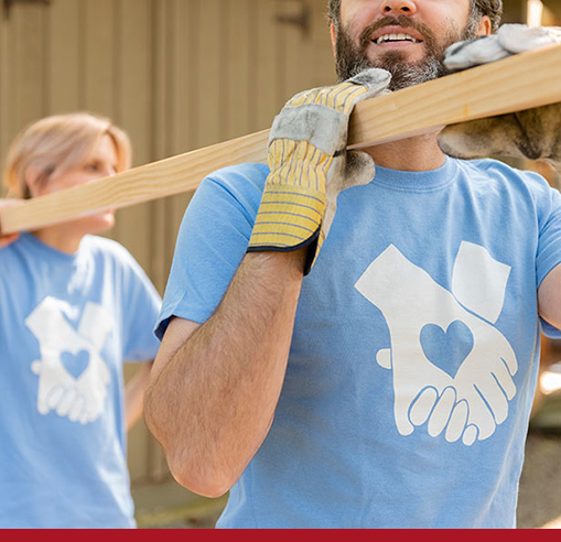 image of man and women carrying a piece of wood while volunteering