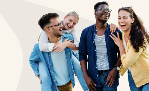 Four friends standing together and laughing.