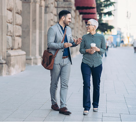 Image of two professional coworkers talking while walking outside