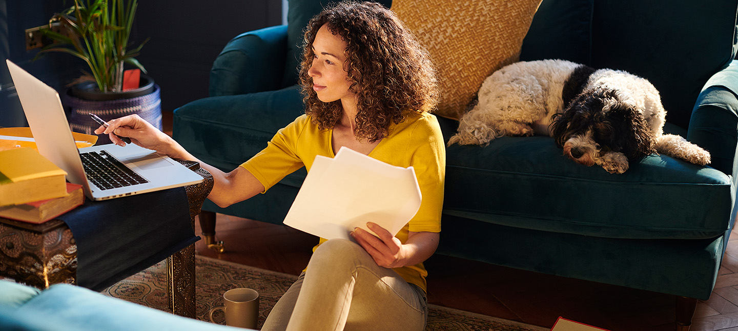 woman sitting on the floor of her livingroom looking at her laptop