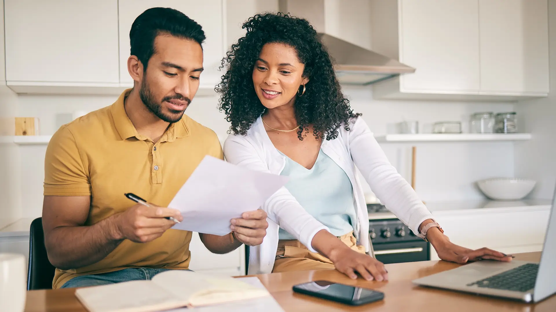 A couple in their kitchen reviewing documents and planning.