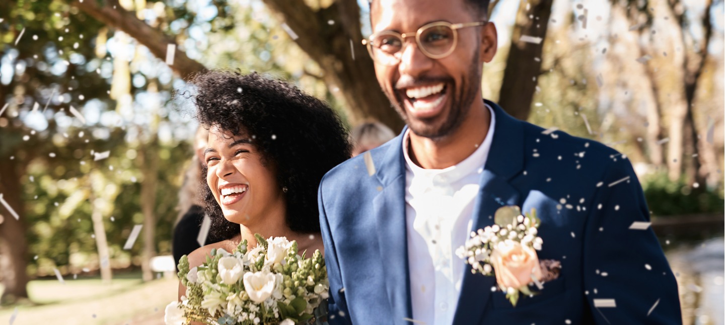 Shot of a happy newlywed young couple getting showered with confetti outdoors on their wedding day


