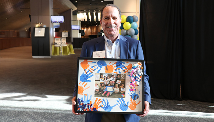 Matt Gendron, Ent Chief Engagement Officer, holding a shadow box with kids' painted hand prints